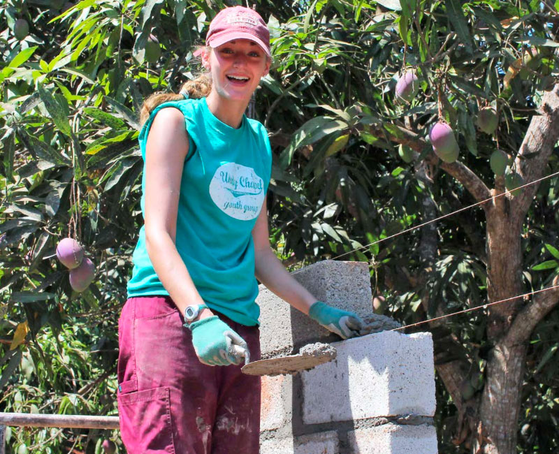 UE Sociology student helping in the community by laying bricks.